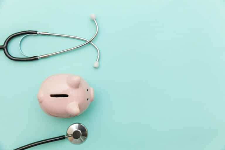Piggy bank with stethoscope on greenish-blue background