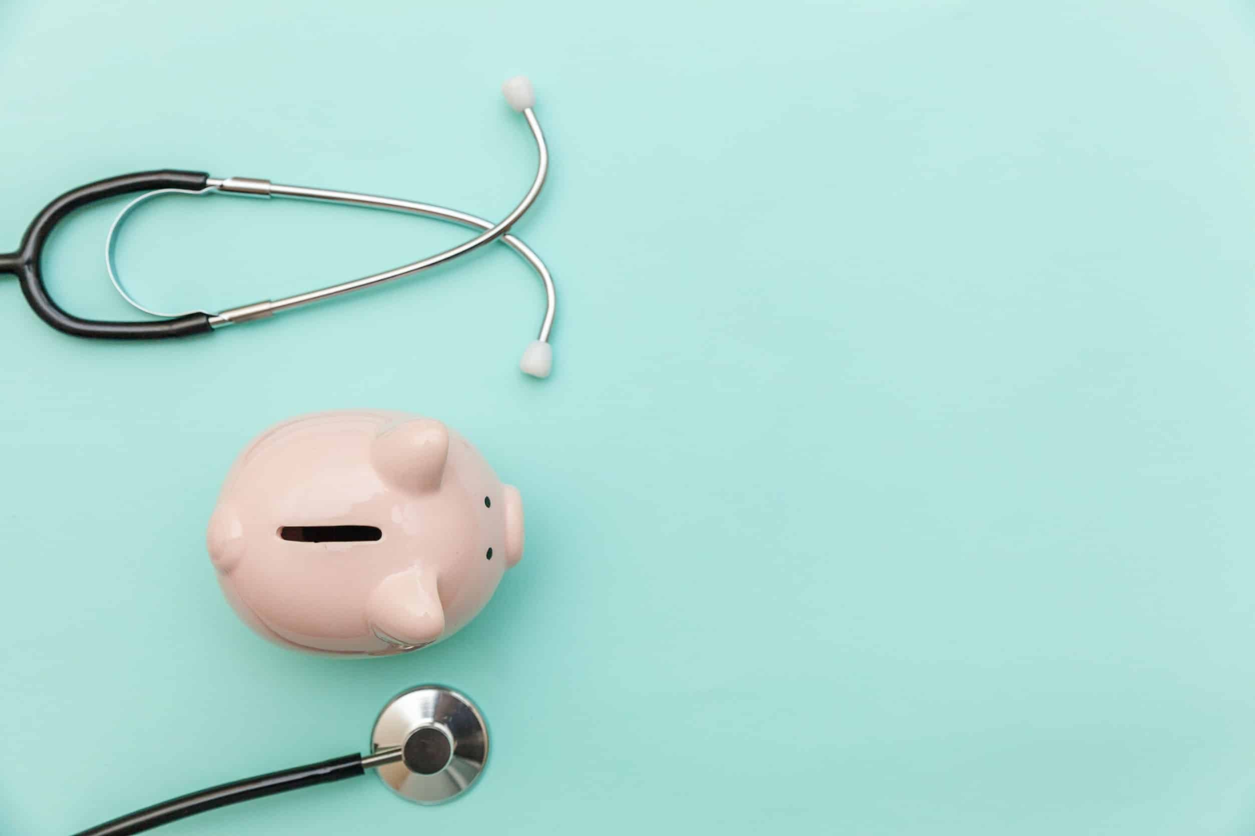 Piggy bank with stethoscope on greenish-blue background
