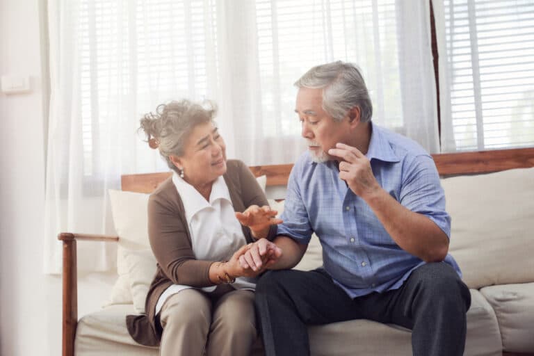 Retired couple with wife taking care of husband sitting on the couch