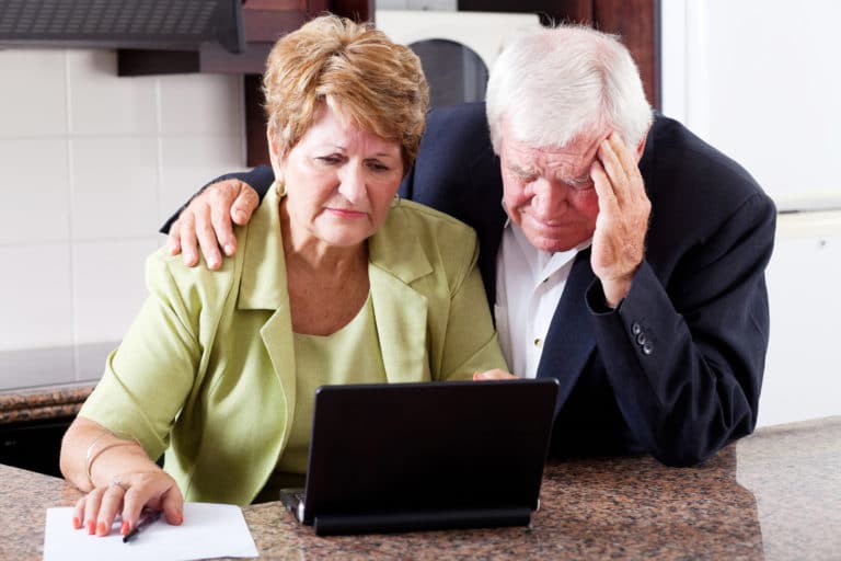 Drowntrodden seniors looking at computer screen