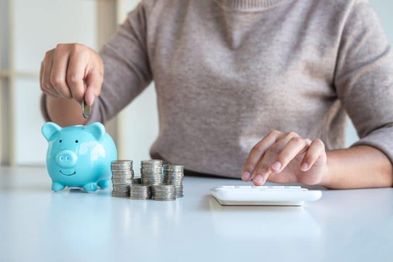 Woman putting coins into a blue piggy bank
